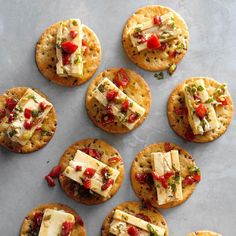 crackers with cheese and vegetables on them are arranged on a baking sheet, ready to be eaten