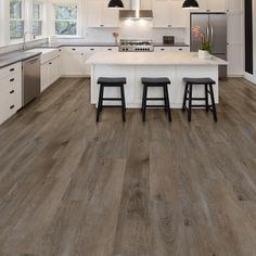 a large kitchen with white cabinets and wood flooring on the walls, along with two bar stools