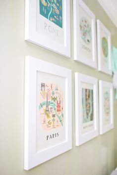 several framed maps hang on the wall above a crib in a child's room