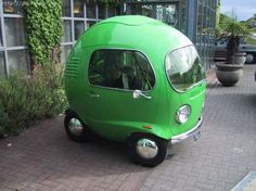 a small green car is parked on the side of the street