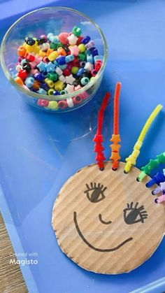 a child's craft made out of construction paper and plastic beads on a blue tray