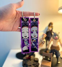 a pair of purple earrings is being held by a person with two other figures in the background