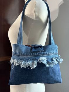 a denim bag with fraying on the bottom and inside, sitting on a mannequin's head