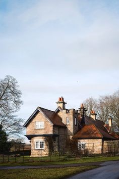 a large brick house sitting on top of a lush green field