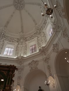 an ornate ceiling with chandeliers and windows in a room filled with white walls