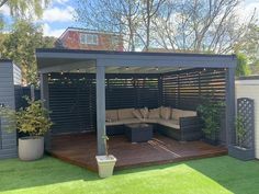 an outdoor living area with couches and lights on the roof, surrounded by grass