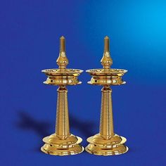 two golden candlesticks sitting side by side on a blue background with one candle holder in the middle