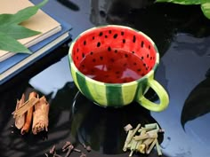 a watermelon cup sitting on top of a black table next to some spices