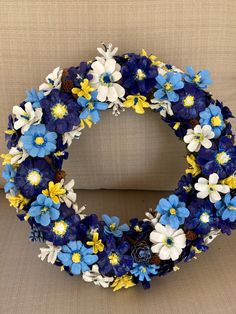 a blue and white wreath with yellow flowers on the front is sitting on a chair