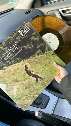 a person holding up a record in their car seat with the cover pulled down and an album on top of it