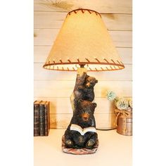 a lamp that is sitting on top of a table with a bear reading a book