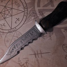 a knife that is sitting on top of a paper with pentagrams in the background