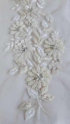 an embroidered white fabric with flowers and pearls on the bottom, as well as beads in the middle