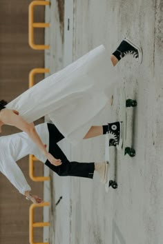 a woman standing next to a wall wearing black and white shoes