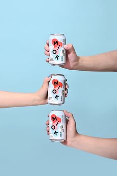 three people holding cans of milk with hearts painted on them