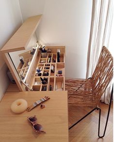 a wooden table topped with lots of drawers filled with jewelry next to a chair and window