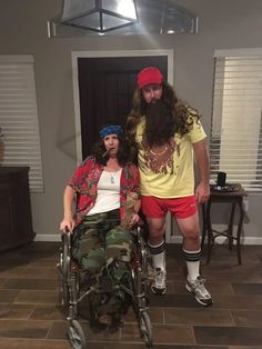 a man in a wheelchair with a long beard standing next to a woman wearing red shorts