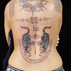 the back of a woman's body with tattoos on her stomach and two tigers