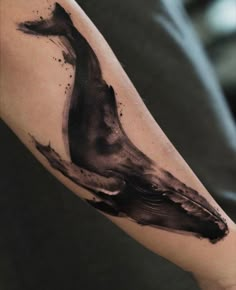 a black and grey whale tattoo on the right upper arm with watercolor splashes