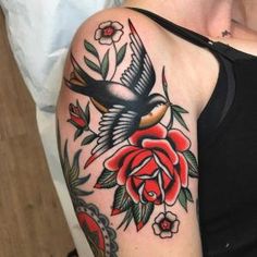 a woman's arm with a bird and roses tattoo on her left upper arm