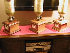 three wooden speakers sitting on top of a pink table next to a tv monitor and remote control