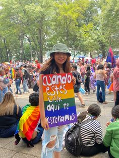 a woman holding a sign in front of a group of people sitting on the ground