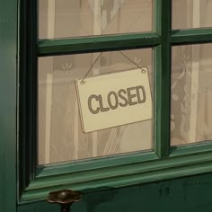 a closed sign hanging from the side of a green door