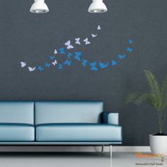 a living room with a blue couch and wall decals on the walls that have butterflies coming out of it