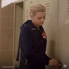 a woman standing in front of a locker with her hand on the door and looking down