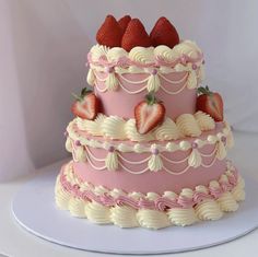 a three tiered pink cake with strawberries on top and white icing around the edges