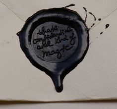 a waxed seal with the words magic written on it, and some ink drops