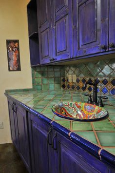 a kitchen counter with blue cabinets and a bowl on the sink in front of it