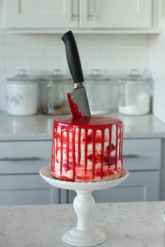 a red and white cake sitting on top of a table with a knife stuck in it