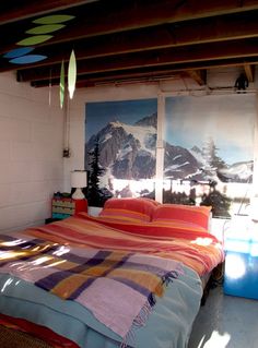 a bed sitting in a bedroom next to a window with mountains on the wall behind it