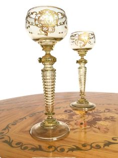 two glass goblets sitting on top of a wooden table next to each other