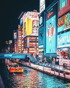 an image of a city at night with boats on the water and billboards in the background