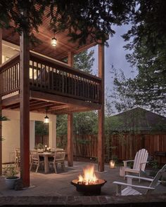 a fire pit sitting in the middle of a patio next to a wooden deck with chairs