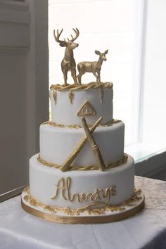 a white and gold wedding cake with two deer figurines sitting on top of it