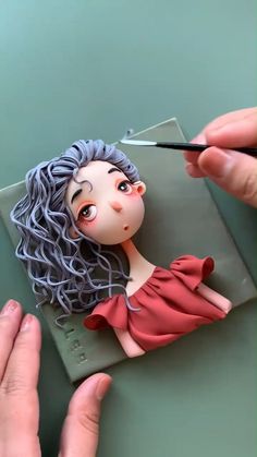 someone is cutting out a doll with scissors on a piece of paper that looks like she has gray hair