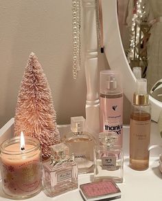 various perfumes and christmas tree decorations on a counter top with a mirror in the background