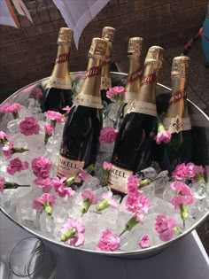 four bottles of champagne in ice with pink flowers