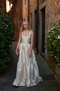 a woman in a white dress is standing outside