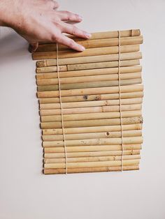 a hand is reaching for bamboo blinds on the wall in front of a person's hand