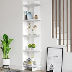 a white book shelf sitting in the corner of a room next to a potted plant