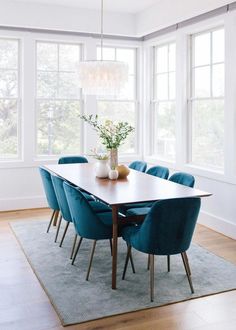 a dining room table with blue chairs and a vase filled with flowers on top of it