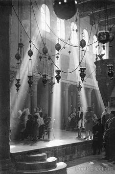 an old black and white photo of people standing in front of some chandeliers