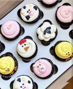 twelve cupcakes with different colored frosting designs in a box on a table