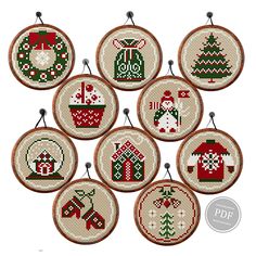 six cross stitch christmas ornaments hanging from hooks