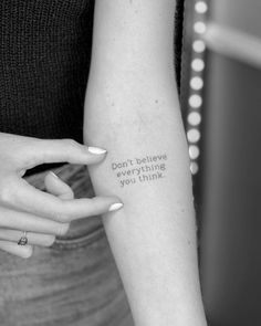 a woman with a tattoo on her arm saying don't believe everything you think