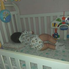 a baby is sleeping in a crib with toys on the wall and floor behind it